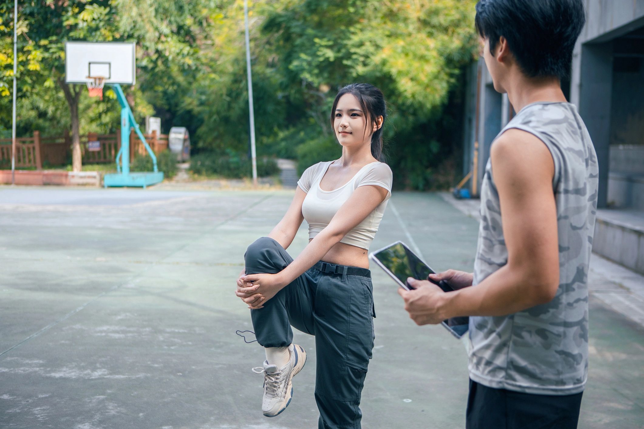 Coach guiding a client through an outdoor workout while reviewing a plan